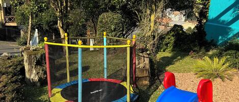 A playground with a trampoline and a blue slide.