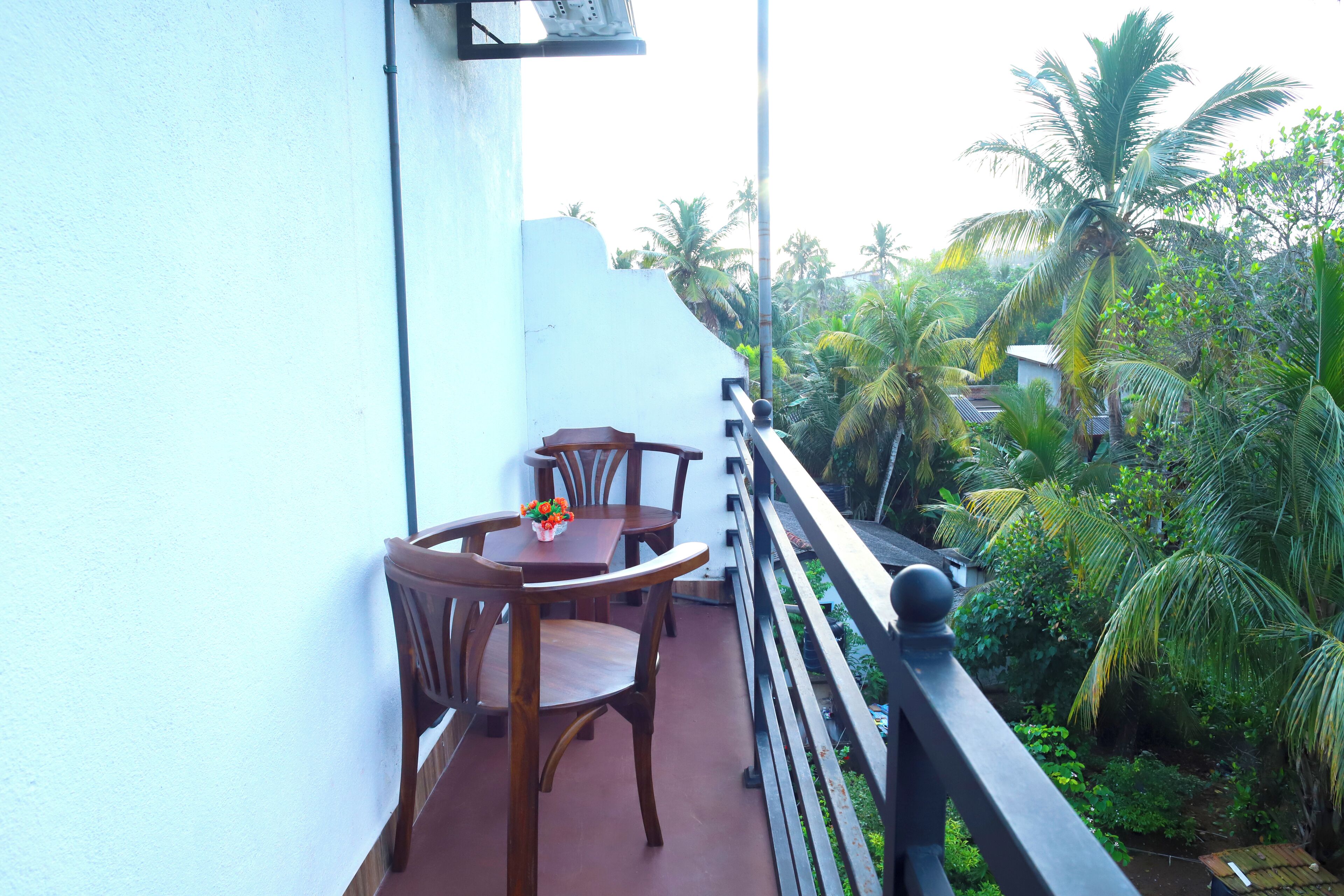 A balcony with wooden furniture and a view of lush greenery.