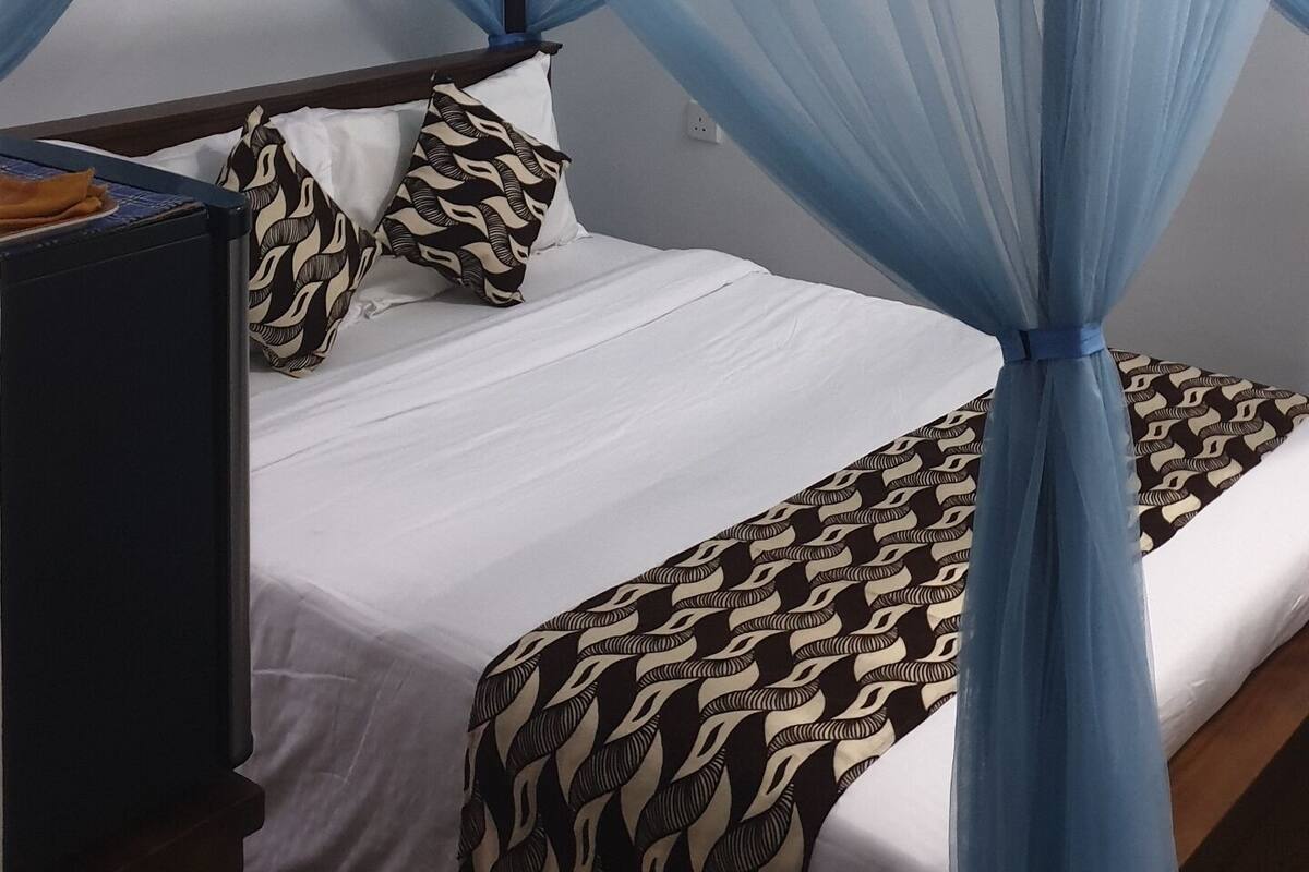 A bed with a canopy, a ceiling fan, and a bedside table.