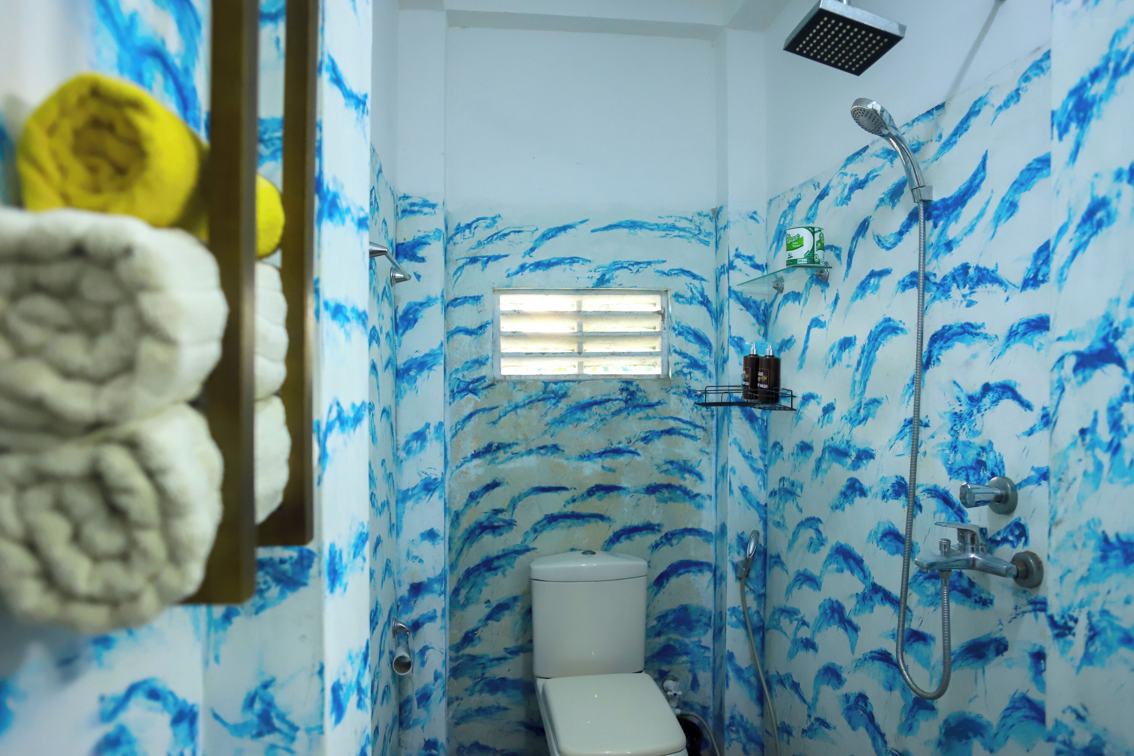 A bathroom with a toilet, shower, and a window.