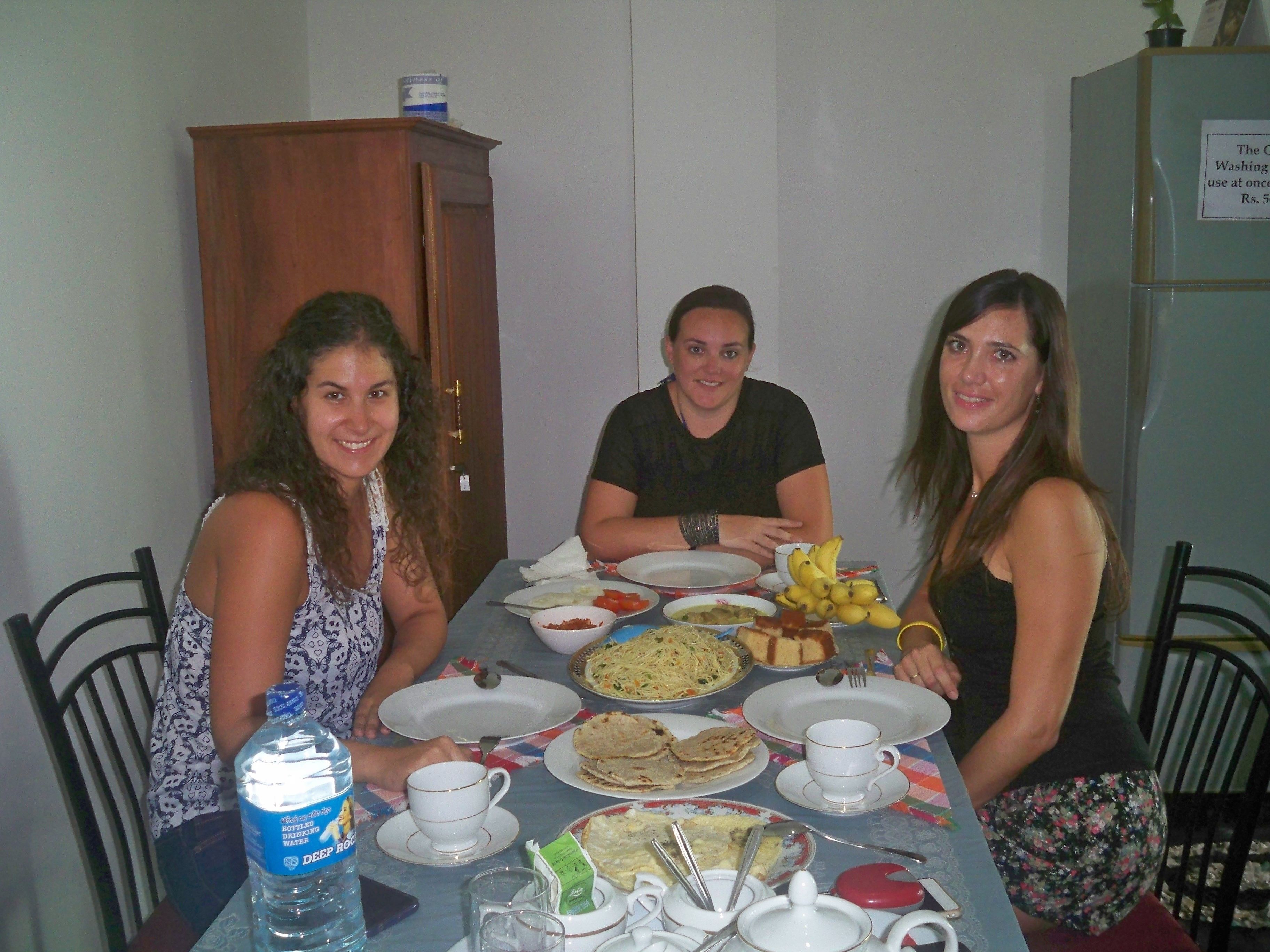 A dining table with plates of food, cups, and a bottle of water.