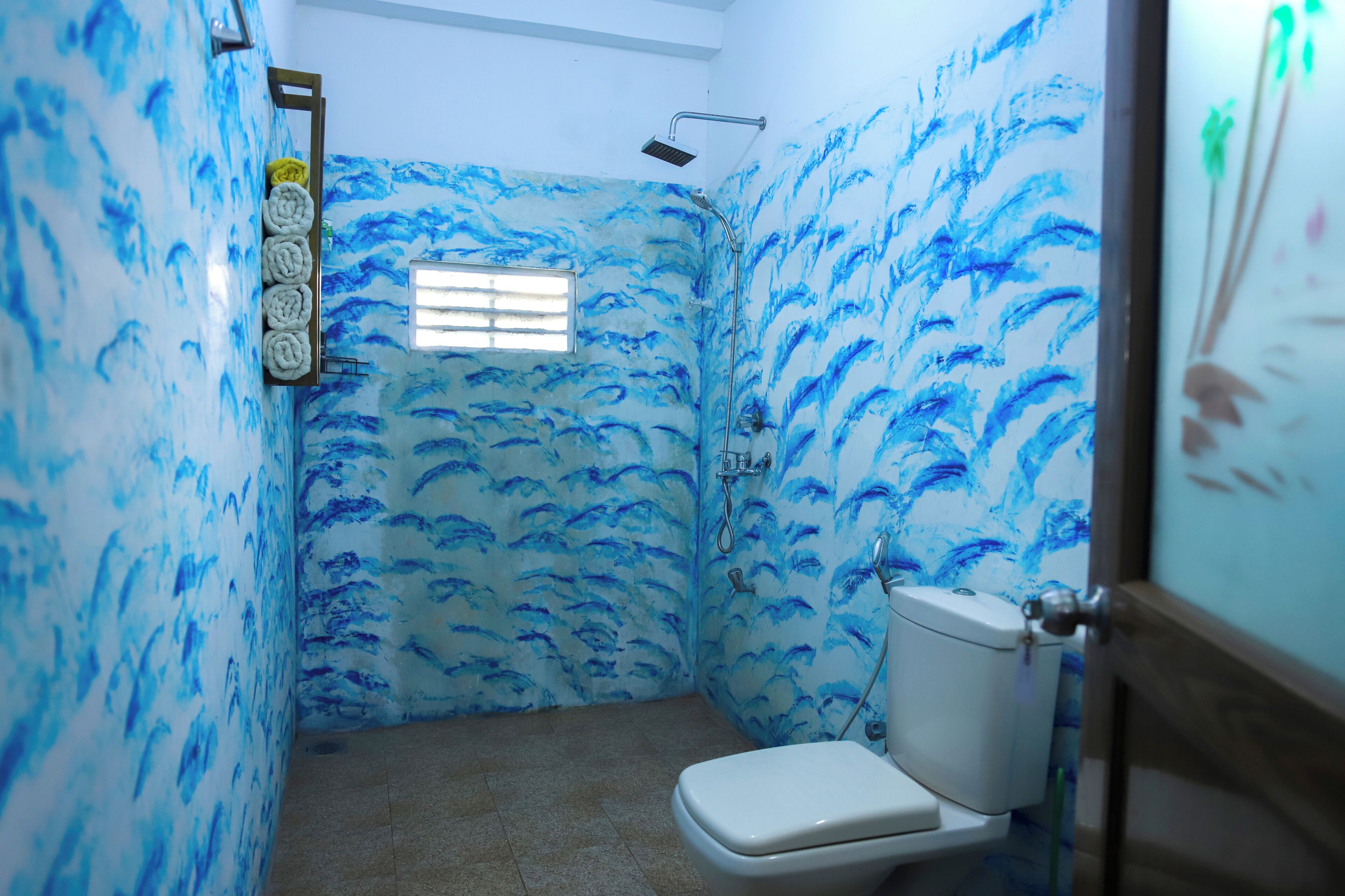 Een kleine badkamer met een douche, toilet en raam.
