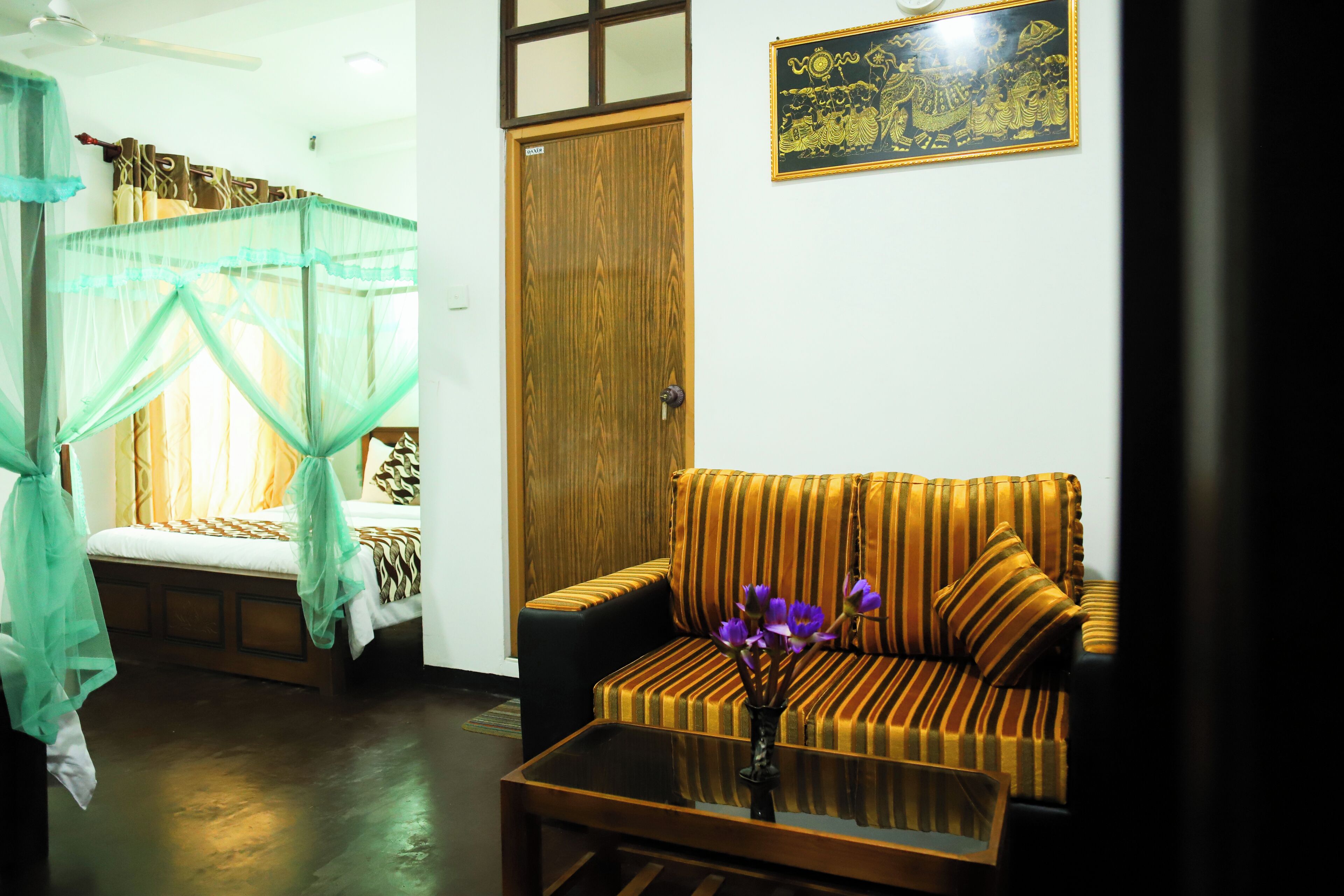A room with a bed, a sofa, a coffee table, and a wooden door.