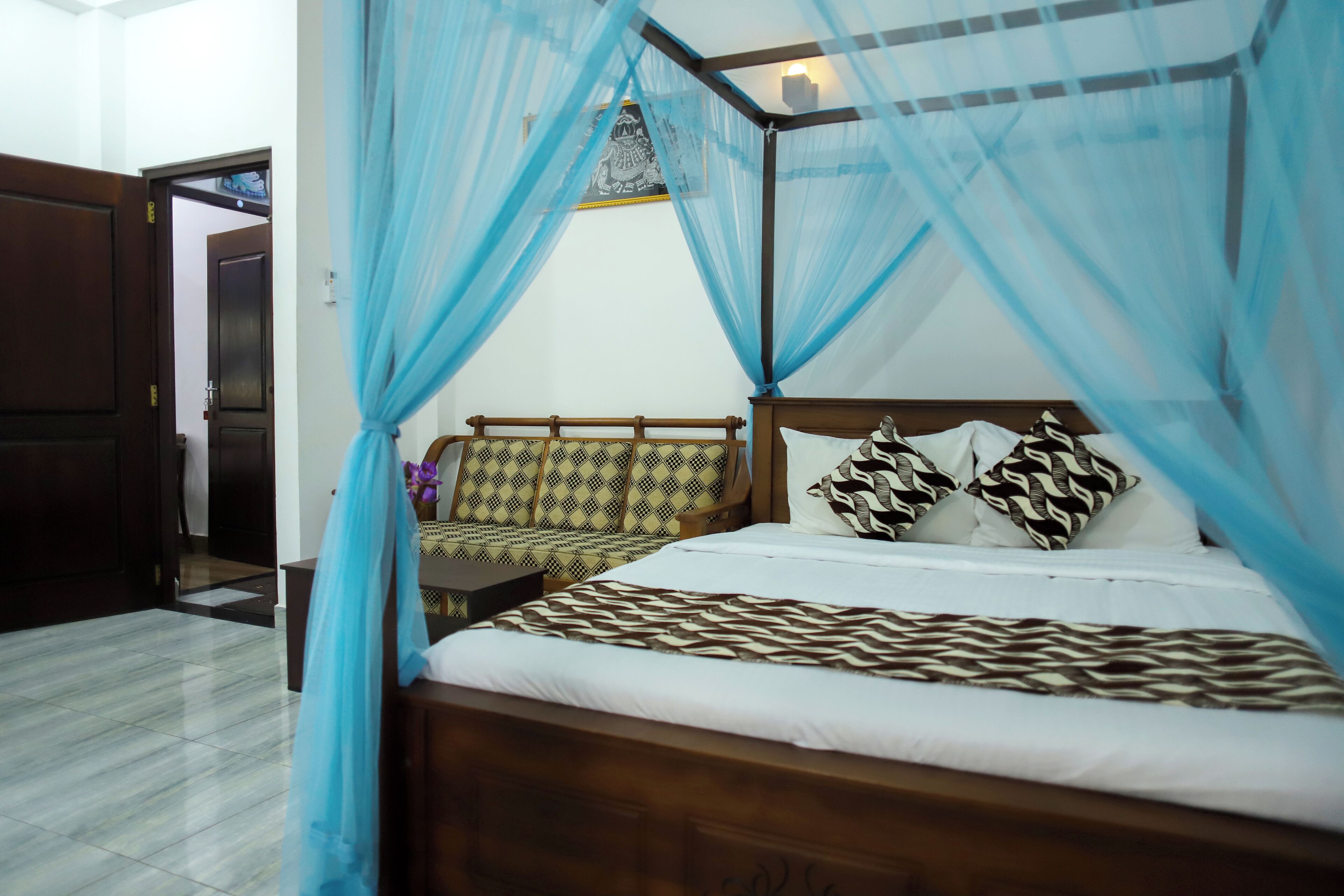 A bedroom with a bed, a nightstand, a wooden bench, and a canopy.
