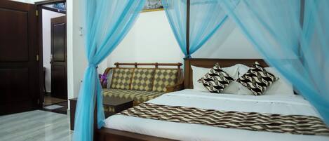 A bedroom with a bed, a nightstand, a wooden bench, and a canopy.