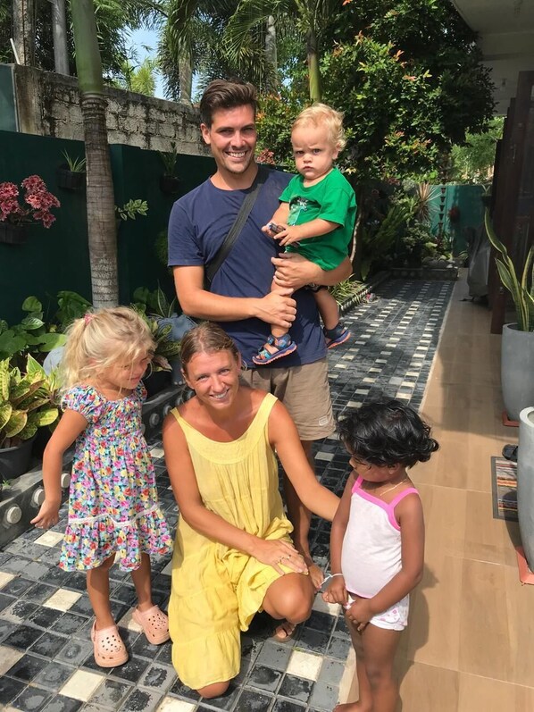 A family of four in a courtyard with a tiled floor, surrounded by greenery and potted plants. - Village Star Rest Mirissa Sri Lanka (Mirissa)