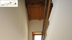 A staircase with granite steps and a wooden handrail, leading to a room with a window. - Appartamento Valeriano (Livigno)