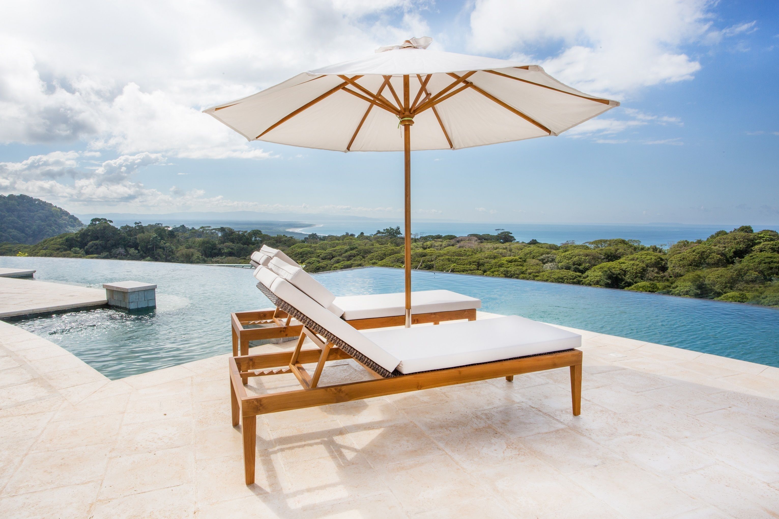 Un espace aménagé au bord de la piscine, avec deux chaises longues en bois et un grand parasol.