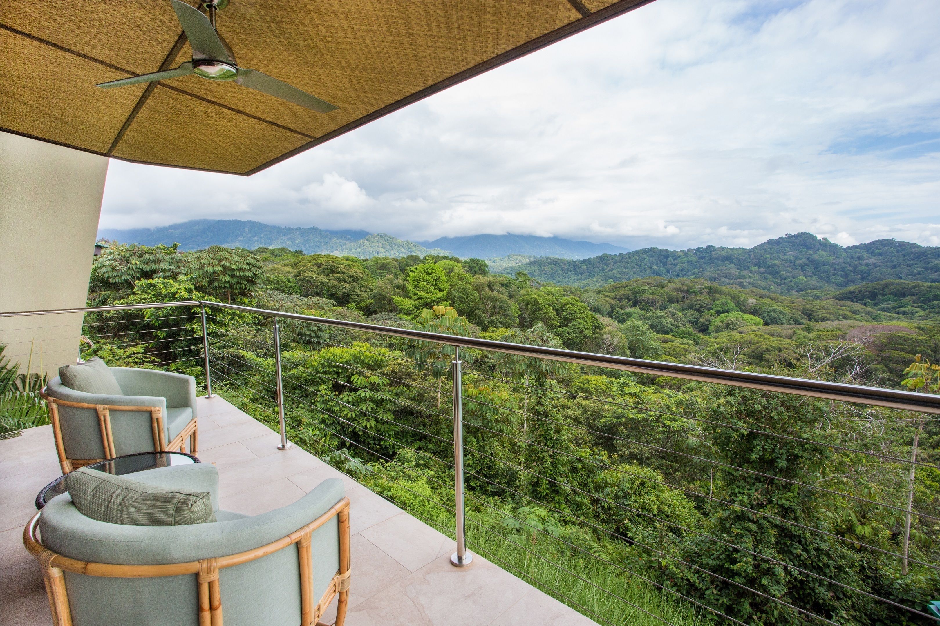 Ein Balkon mit Korbmöbeln und Blick auf eine üppige Waldlandschaft.