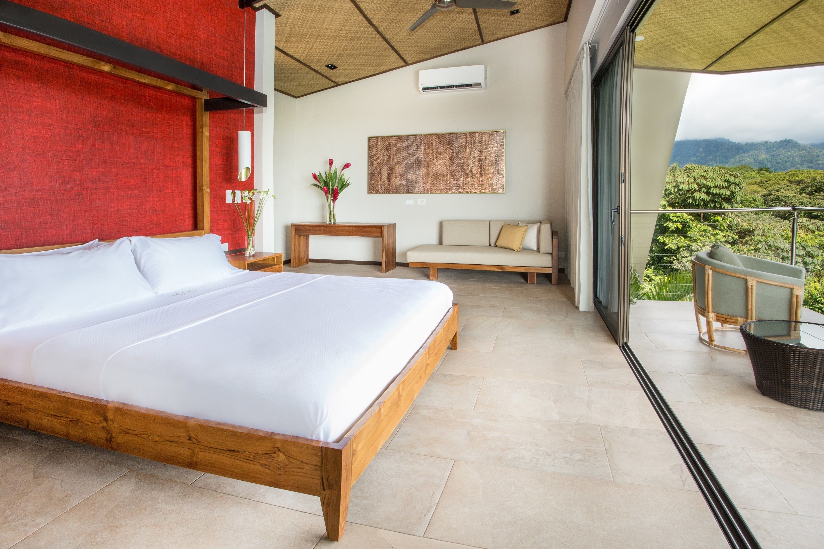 Un dormitorio con una cama grande, un sofá, una mesita y vistas al exterior.
