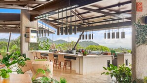 A modern outdoor kitchen area with a bar, seating, and hanging lights. - Hotel Three Sixty - Adults Only (Ciudad Cortés)
