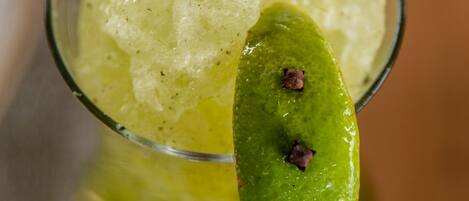 A clear glass with a green garnish and a mint leaf on top.