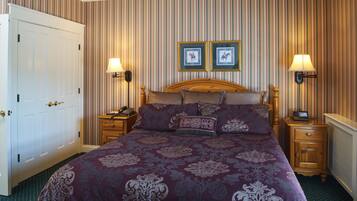 A hotel room with a large bed, two bedside tables, a wooden headboard, and striped wallpaper.