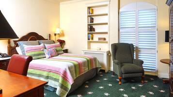 A bedroom with a bed, a chair, a desk, and a bookshelf.