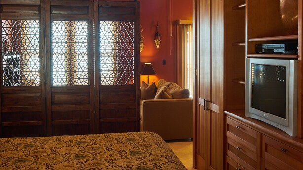 A room with a bed, wooden wardrobe, and a television. - Hotel Mac (Richmond)