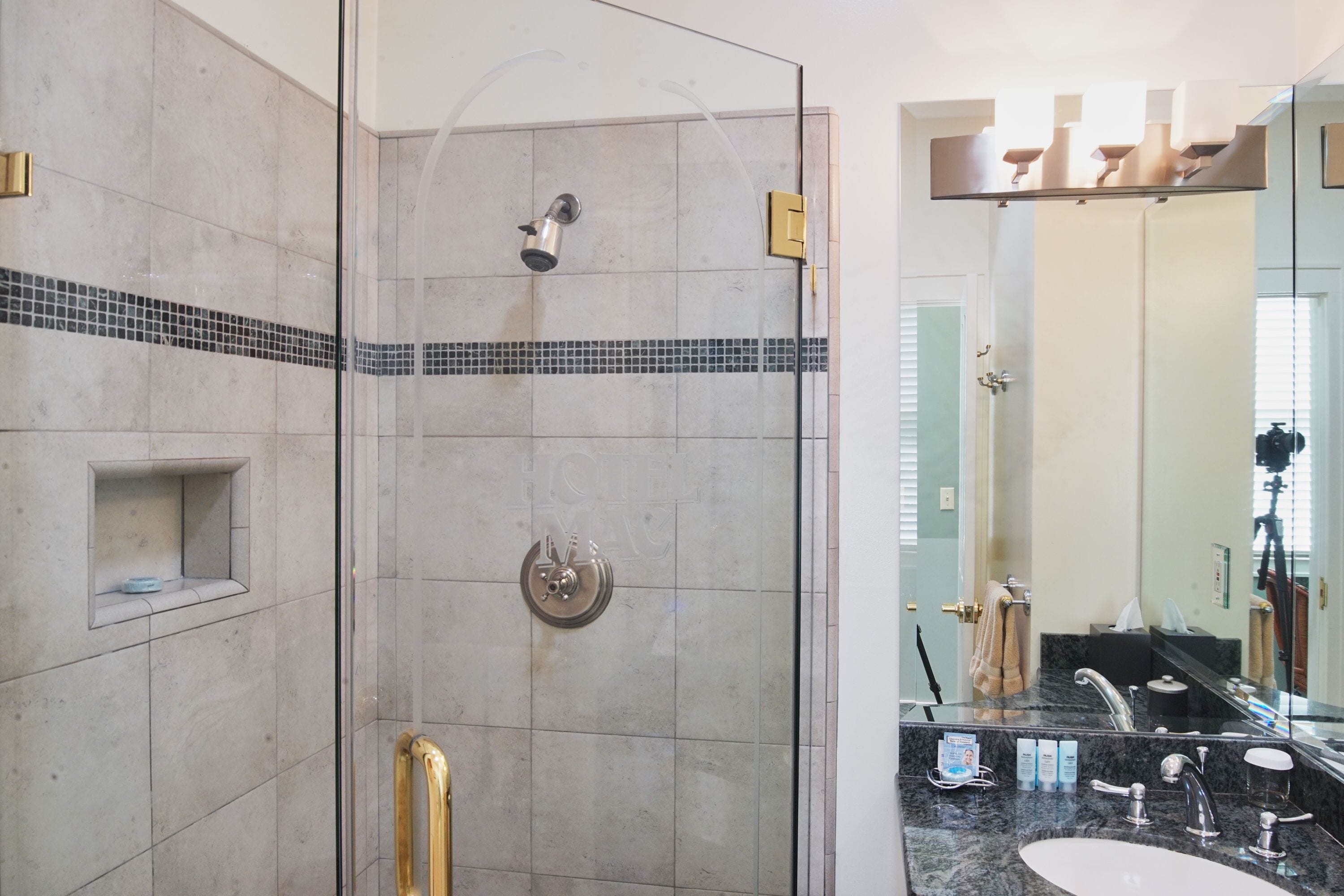 A modern bathroom with a glass-enclosed shower, a vanity with a sink, and a large mirror.