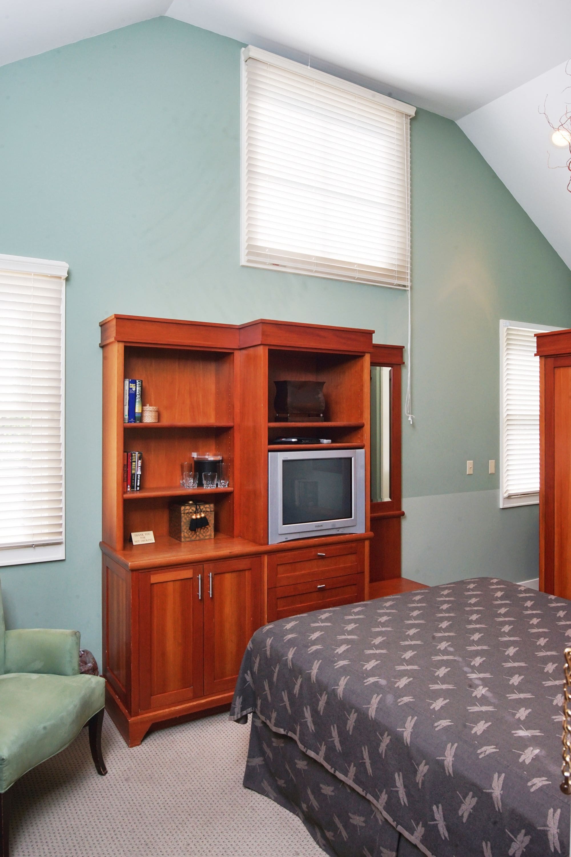 Un dormitorio con una cama, un armario de madera, un televisor y una silla.