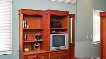 Un dormitorio con una cama, un armario de madera, un televisor y una silla.