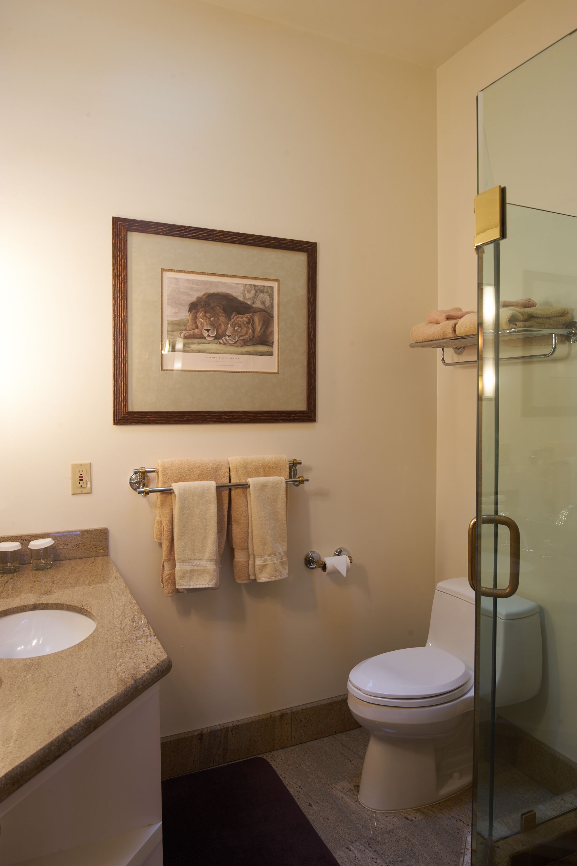 Un baño con lavamanos, inodoro, un cuadro enmarcado y una cabina de ducha de vidrio.