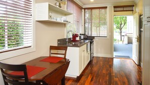 A kitchen with a dining area, wooden flooring, and a view through the window. - Hotel Mac (Richmond)