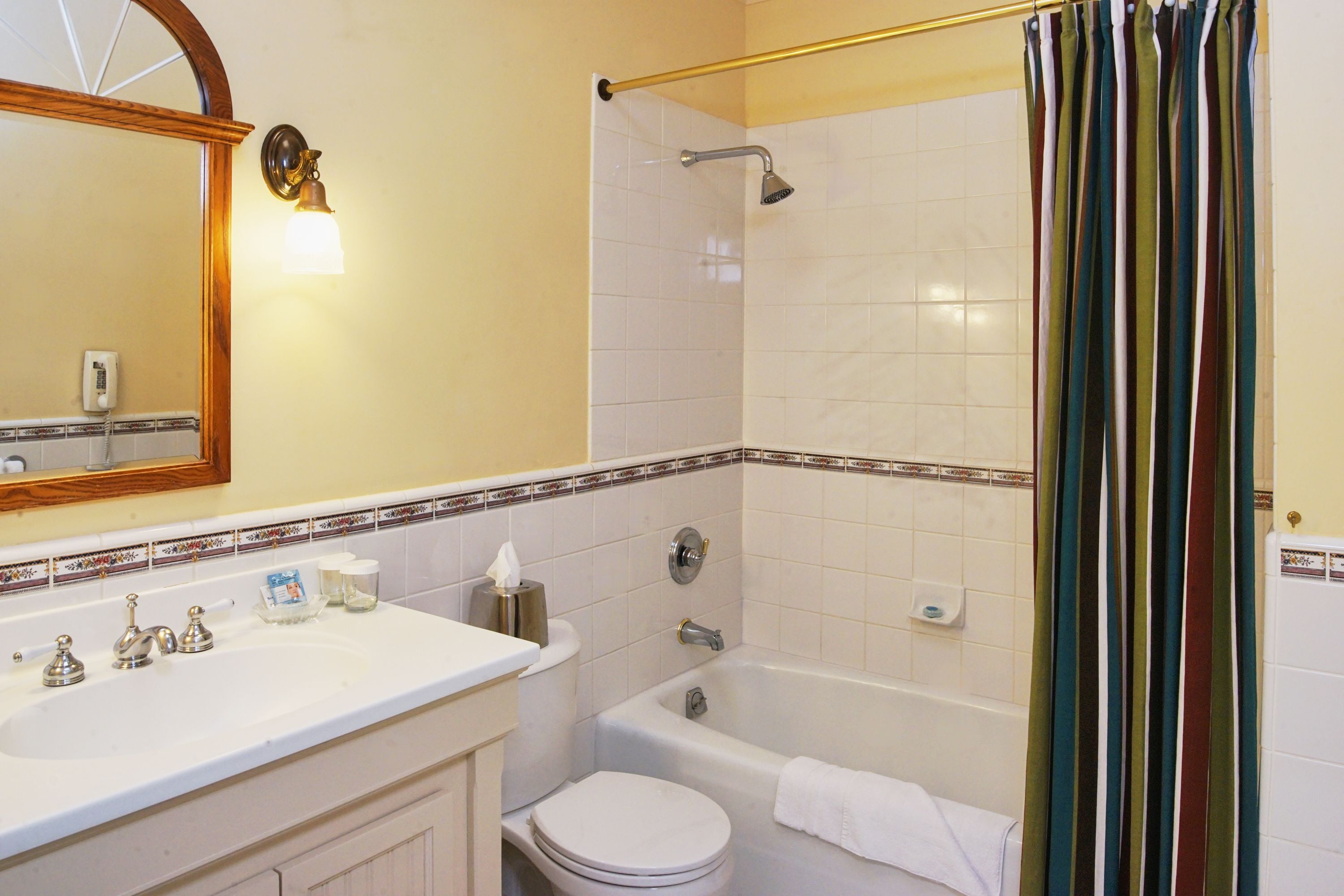 A bathroom with a white sink, toilet, and bathtub. There is a towel hanging on the wall and a shower curtain.