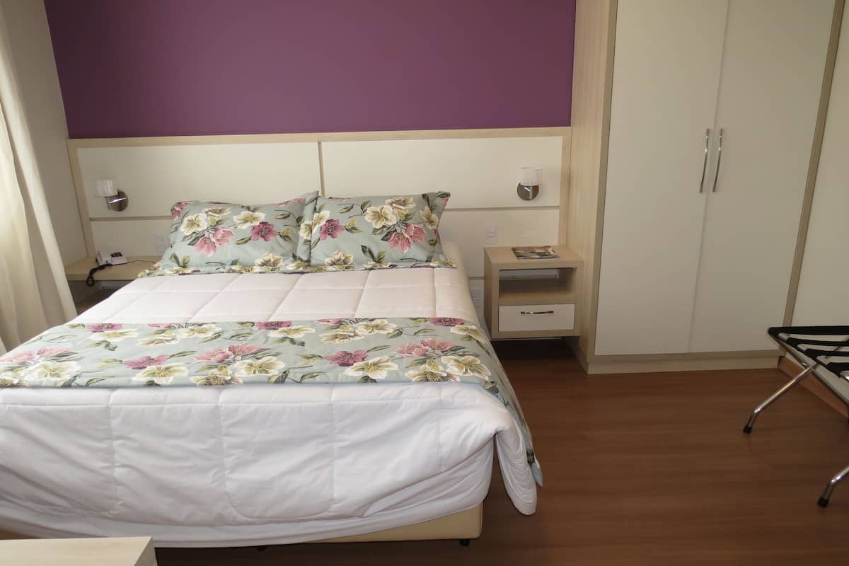 A bedroom with a bed, nightstands, a wardrobe, and a small table.