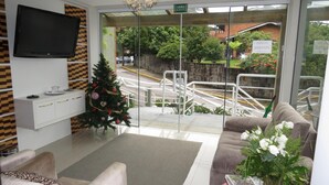 A modern lobby with a flat-screen TV, a Christmas tree, and a red coffee table with a vase of flowers. - Olidal Pousada da Serra (Gramado)