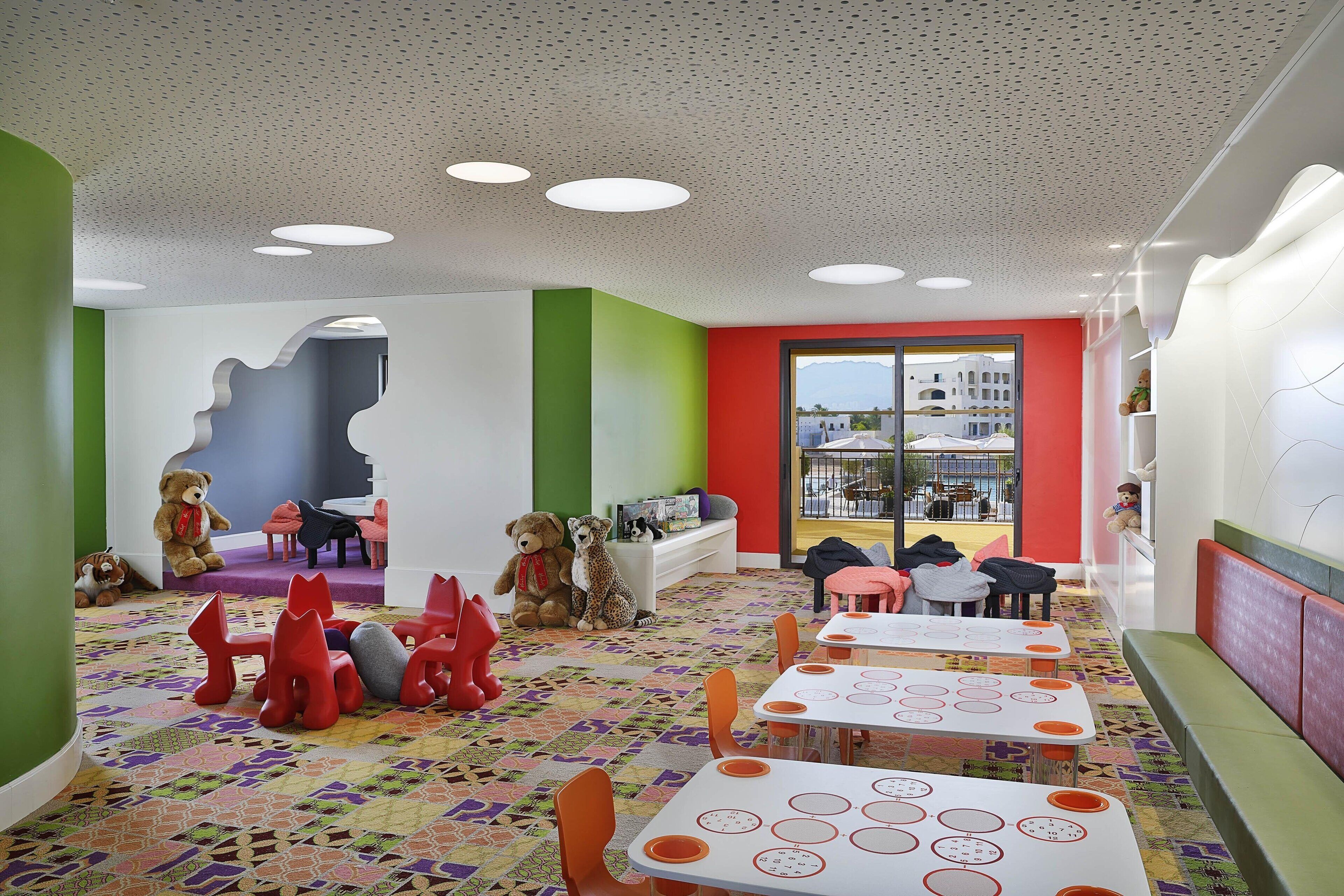 A children's playroom with tables, chairs, and toys.