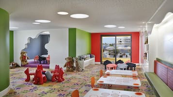 A children's playroom with tables, chairs, and toys.