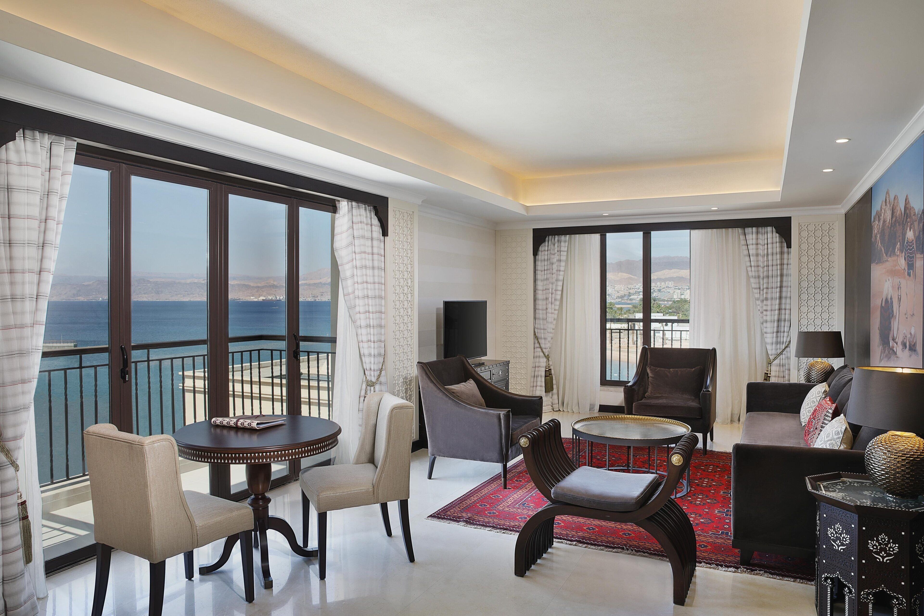 Un salón espacioso con un gran ventanal que ofrece vistas al mar, una mesa de comedor redonda y asientos cómodos.