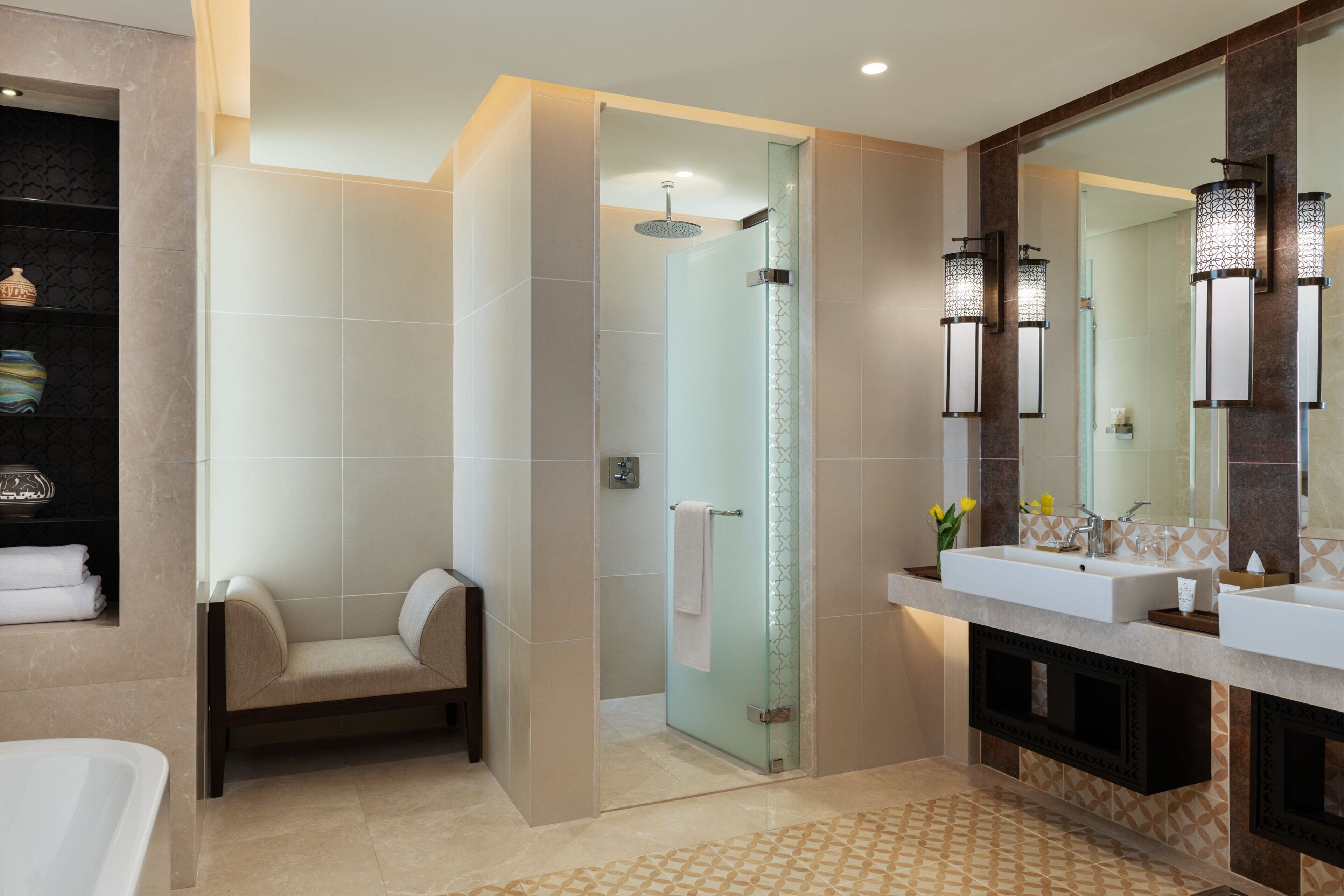 Un baño moderno con ducha envuelta en vidrio, tocador con espejo grande y bañera.