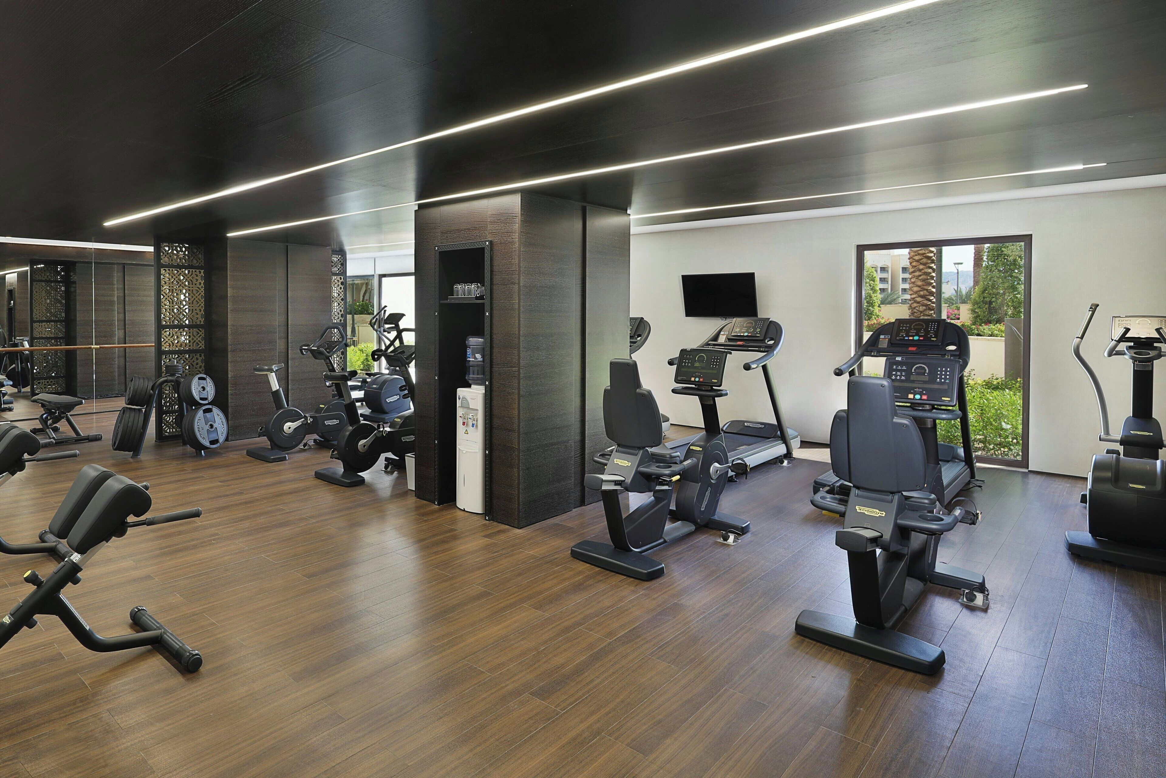Un gimnasio moderno con diversos equipos de ejercicio, incluyendo cintas de correr, bicicletas estáticas y máquinas de pesas.