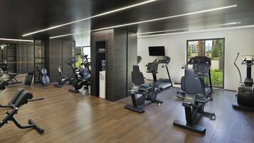 Un gimnasio moderno con diversos equipos de ejercicio, incluyendo cintas de correr, bicicletas estáticas y máquinas de pesas.