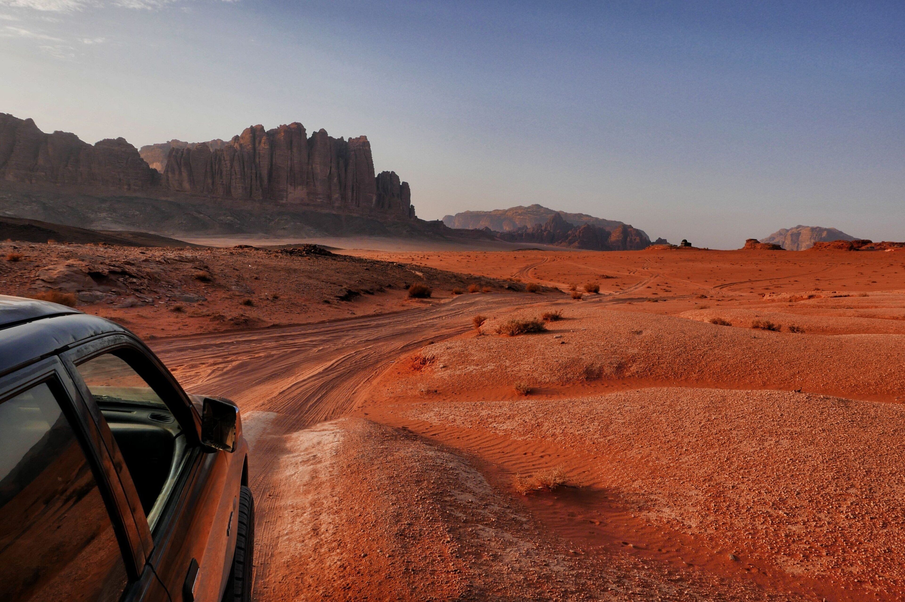 A desert landscape with a car and rocky formations.