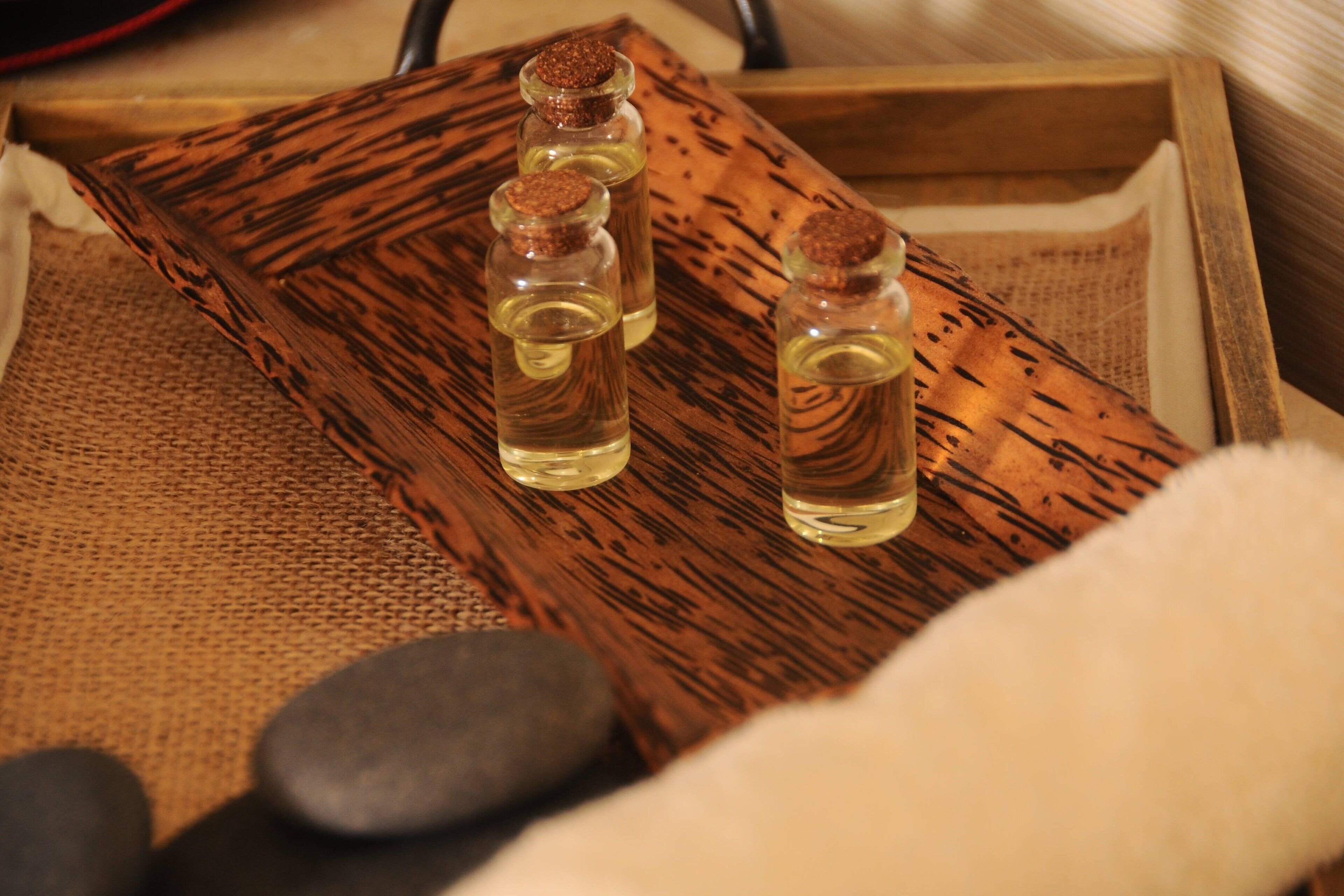 A wooden tray with three small bottles of liquid, possibly essential oils, on a textured surface.