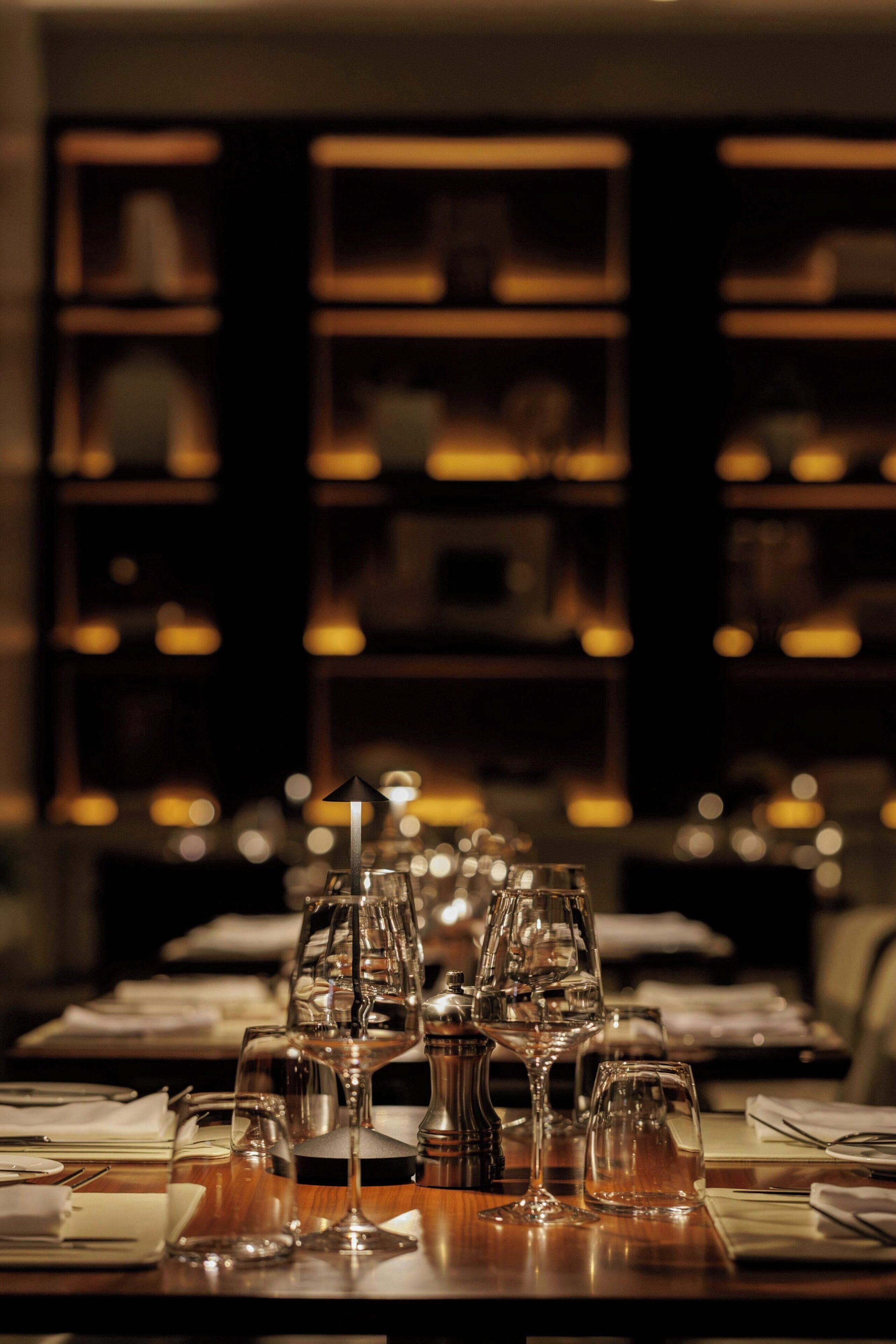 Una mesa de comedor dispuesta con varias copas de vino y un salero y pimentero.