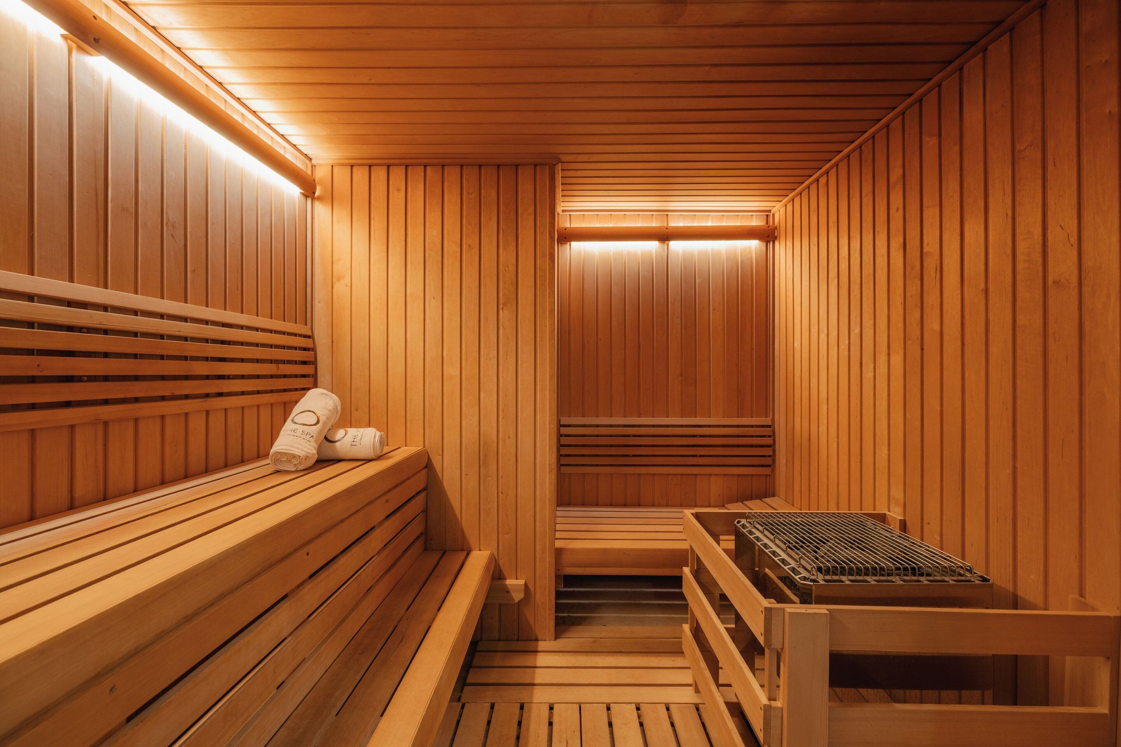 A sauna with wooden benches and benches, a bench with towels, and a bench with a towel.