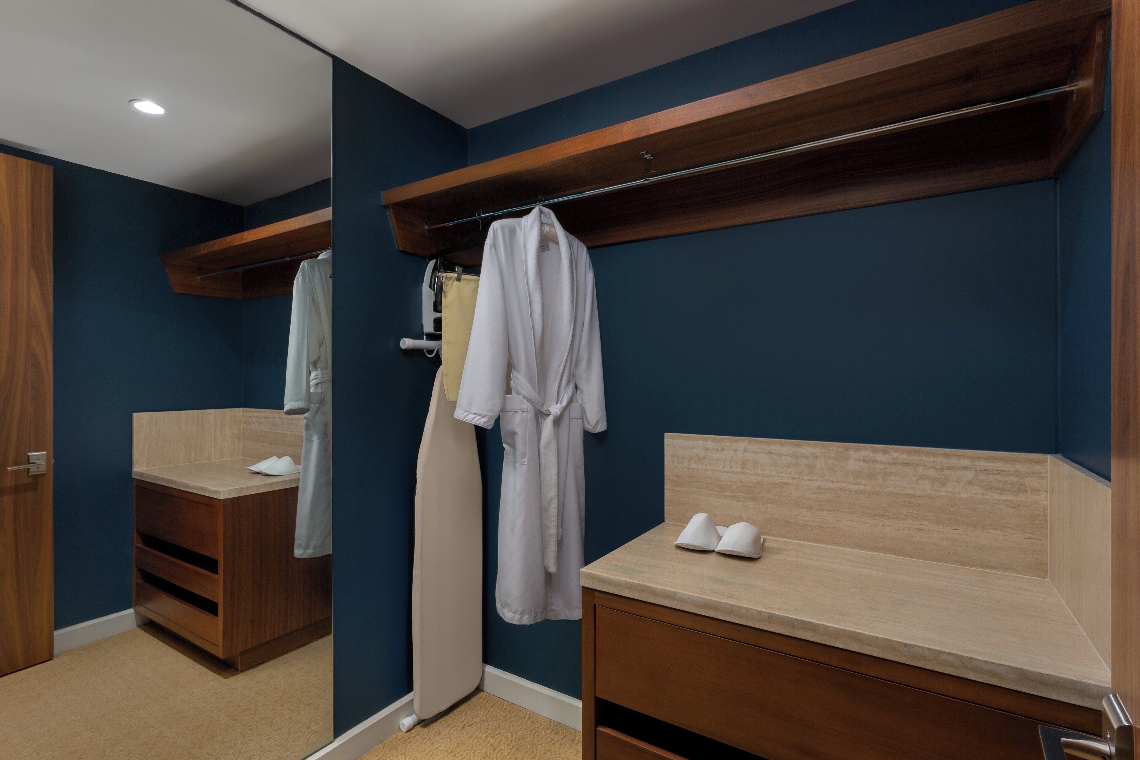 Ein Badezimmer mit einem Holzkosmetikschrank, einem Spiegel und einem auf einem Haken aufgehängten Bademantel.