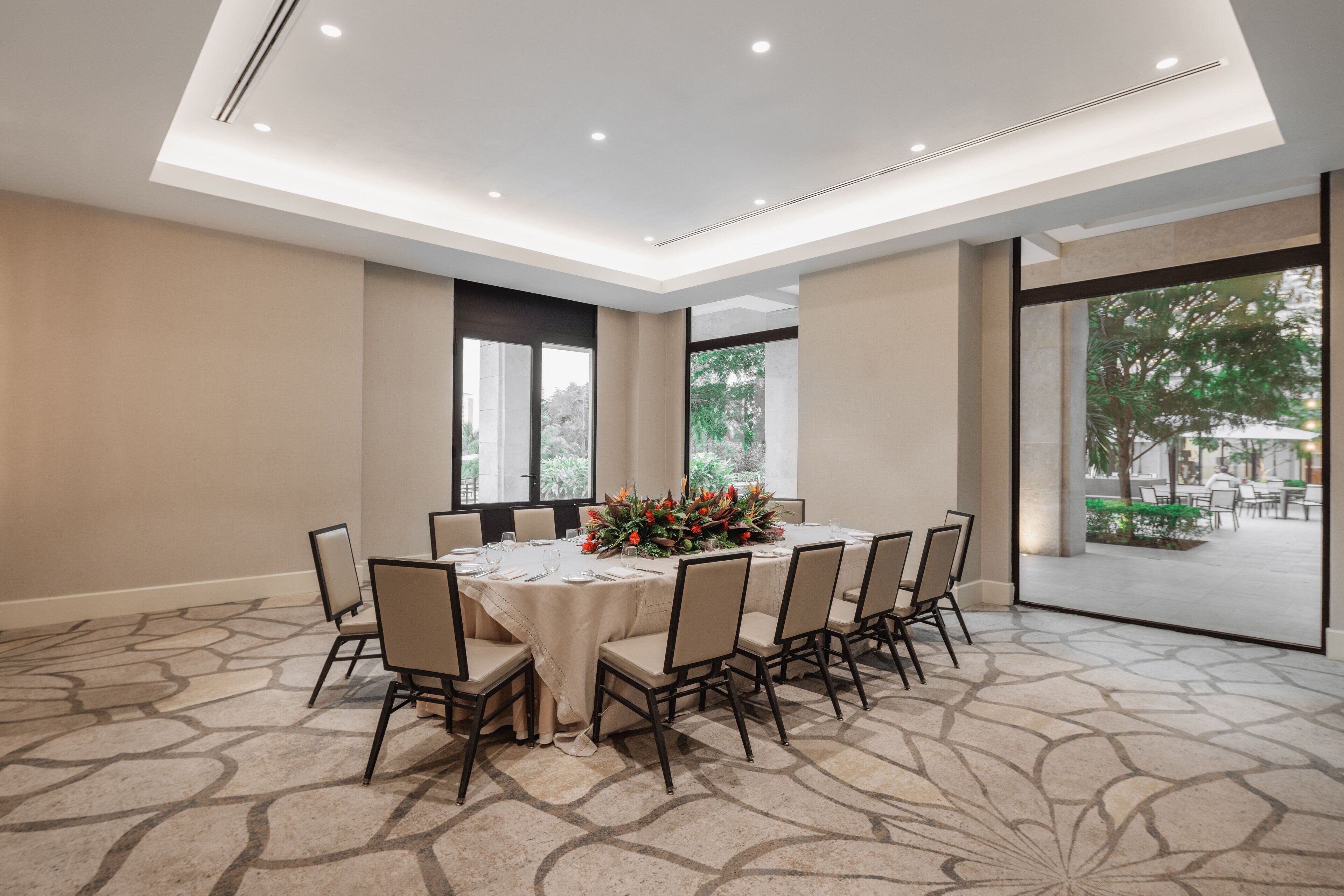 Ein Konferenzraum mit rundem Tisch, Stühlen und einer Blumenarrangements.