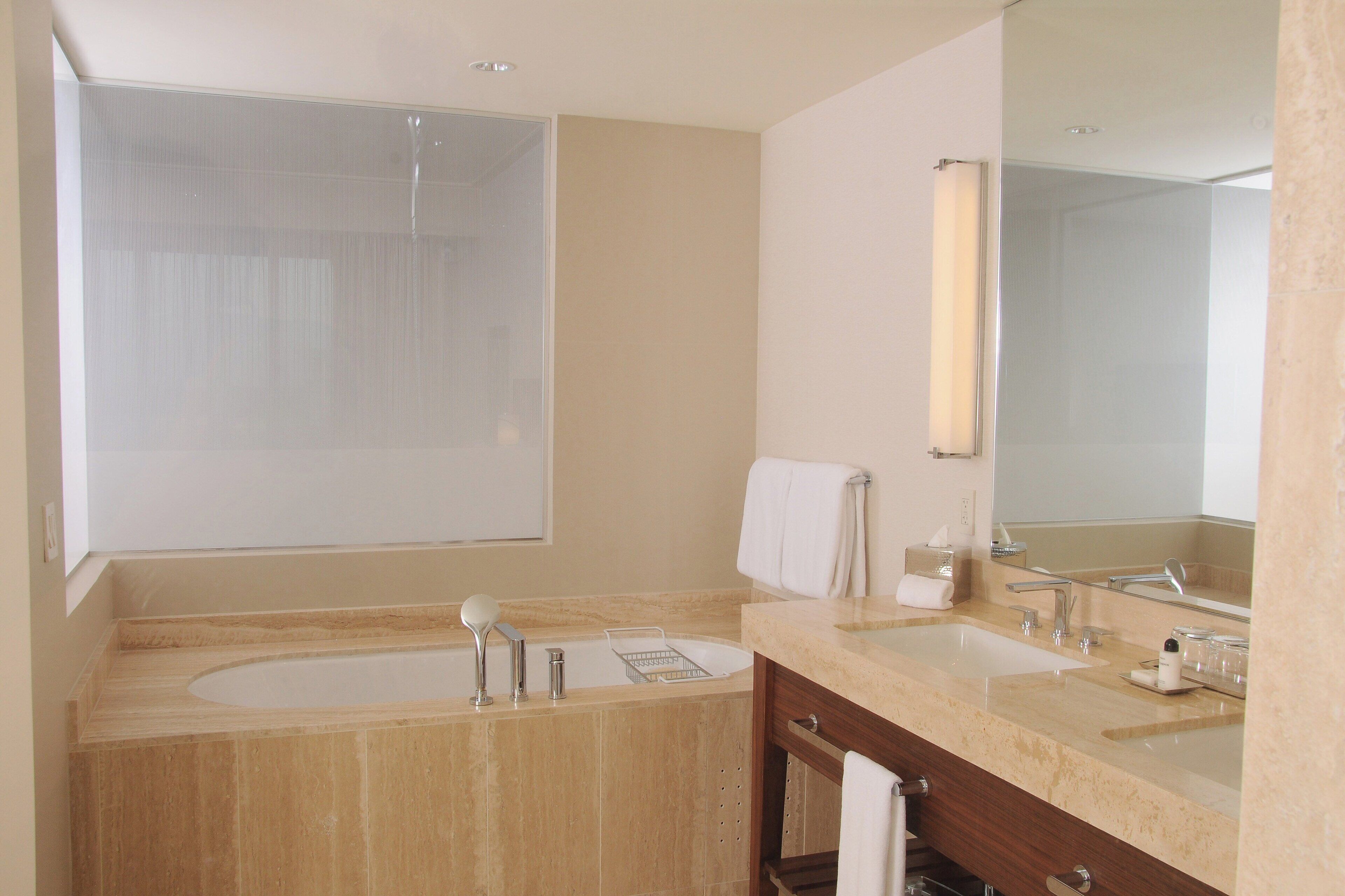 Une salle de bain moderne avec une grande baignoire, deux lavabos, un miroir et un porte-serviettes.