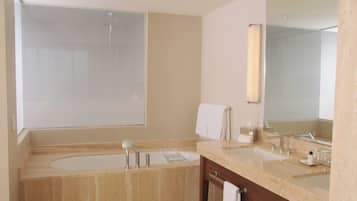 A modern bathroom with a large bathtub, two sinks, a mirror, and a towel rack.