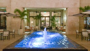 A pool with a central water feature, surrounded by seating areas and potted plants. - The Santa Maria, A Luxury Collection Hotel & Golf Resort, Panama City (Panama City)