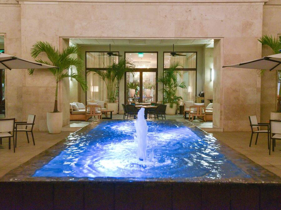 A pool with a central water feature, surrounded by seating areas and potted plants.