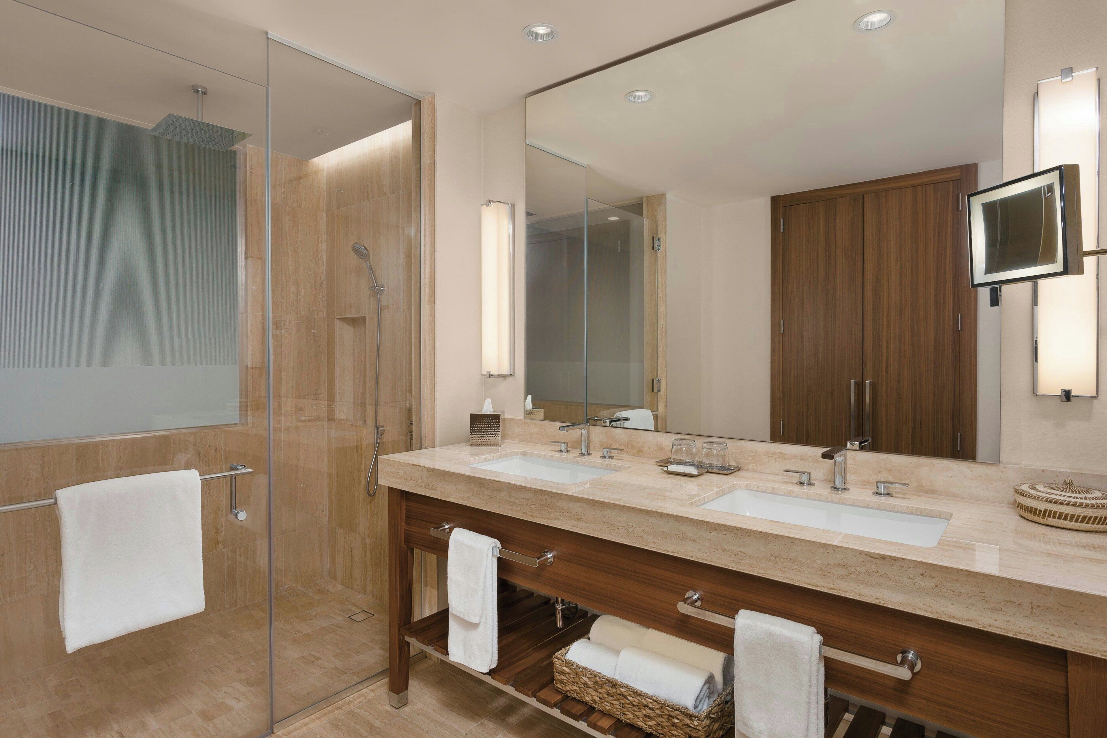 Un baño moderno con cabina de ducha de vidrio, tocador doble y un espejo grande.