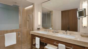 Un baño moderno con cabina de ducha de vidrio, tocador doble y un espejo grande.