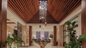 A spacious lobby with a wooden ceiling, a central wooden table surrounded by potted plants, and a marble wall with a large window in the background. - The Santa Maria, A Luxury Collection Hotel & Golf Resort, Panama City (Panama City)