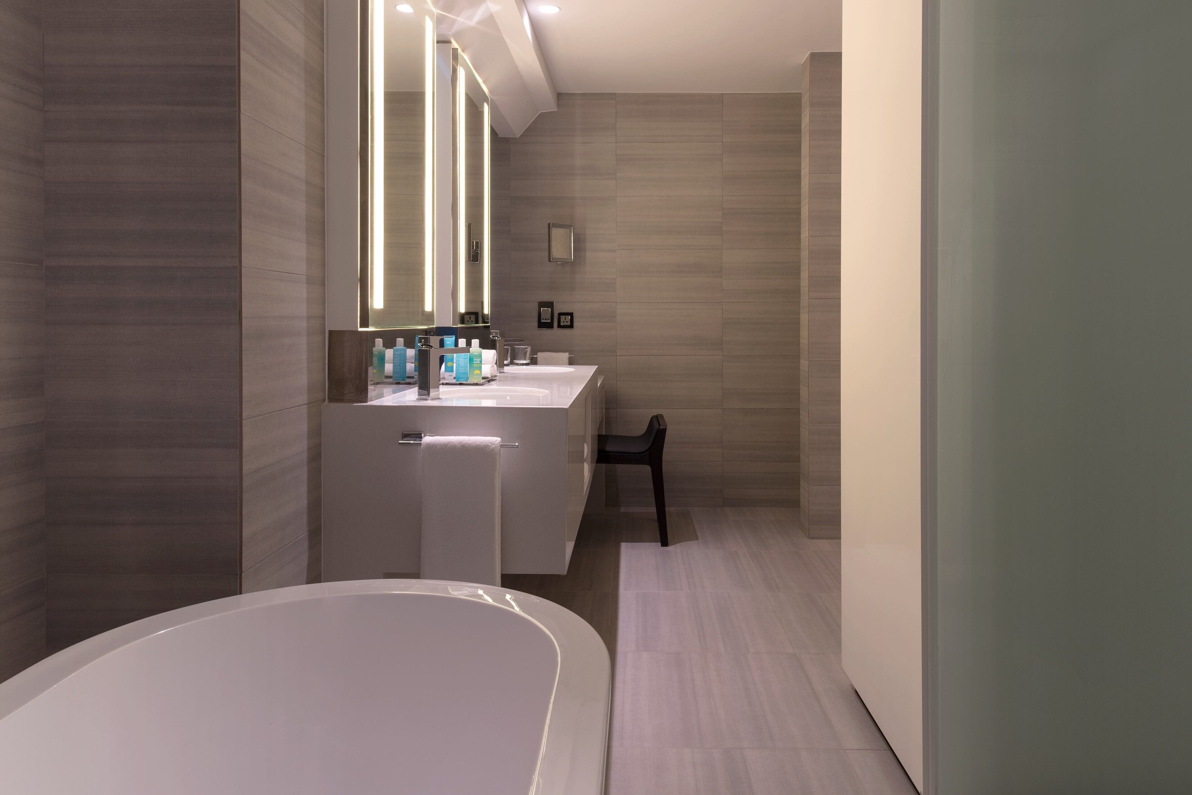 A modern bathroom with a freestanding bathtub, a vanity with a mirror, and a shower area.