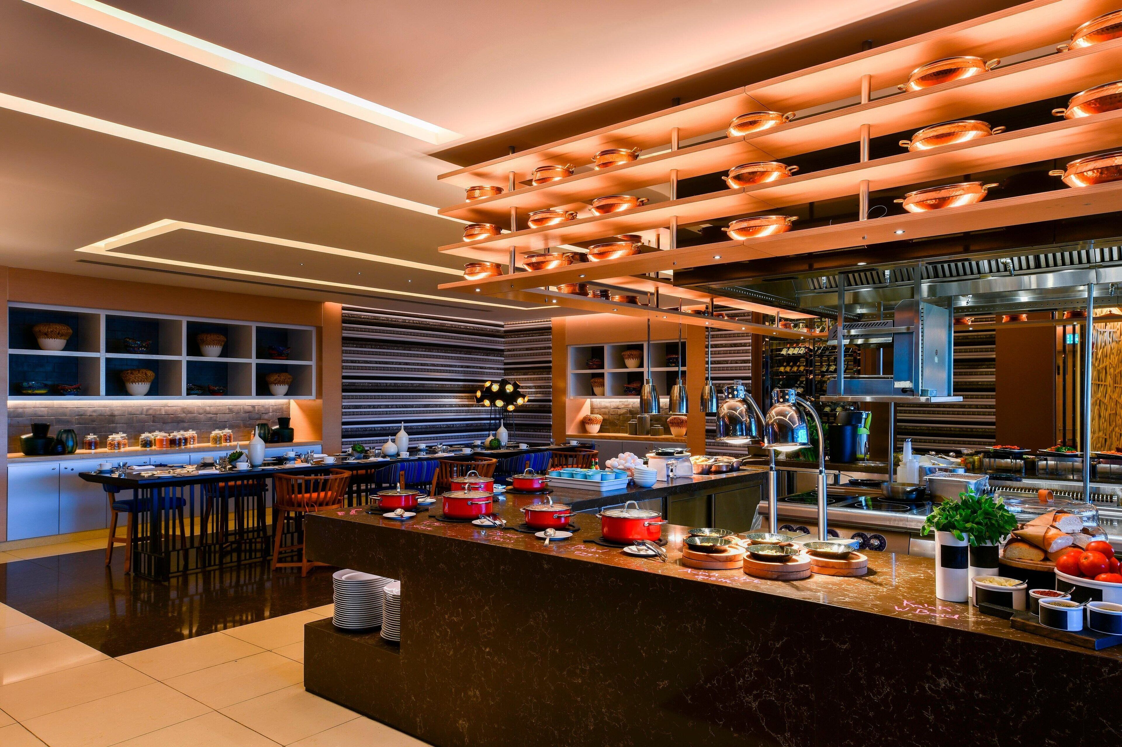 A modern kitchen with a central island, stainless steel appliances, and a variety of cookware and utensils.