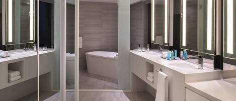 A modern bathroom with two sinks, large mirrors, and a bathtub.