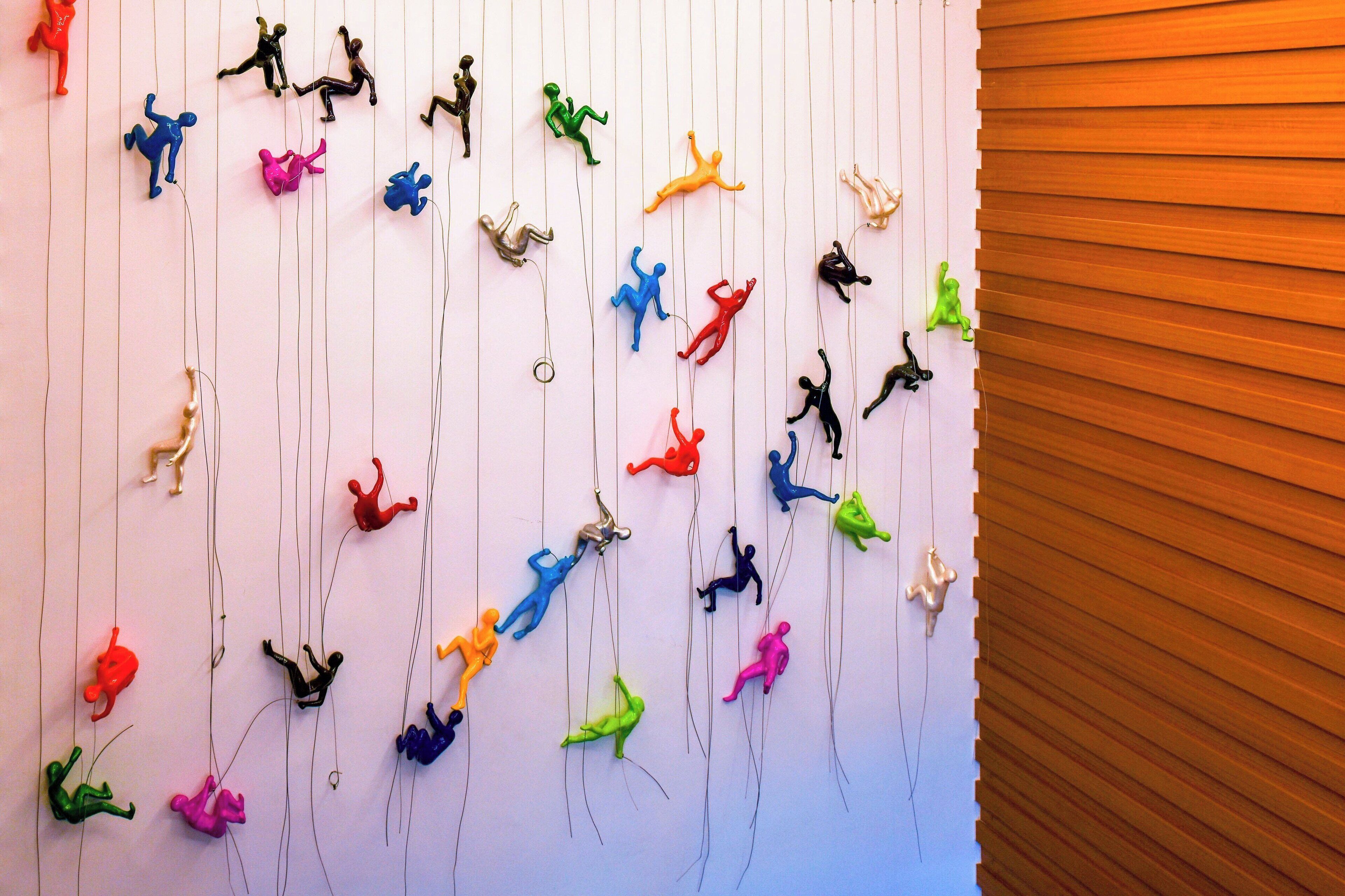 A wall with multiple colorful hanging figures.